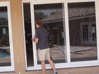 Our installer sliding a new glass door panel by a pool