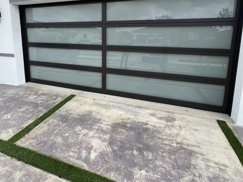 Two-car glass garage door with frosted glass in a black aluminum frame, on one of our jobs