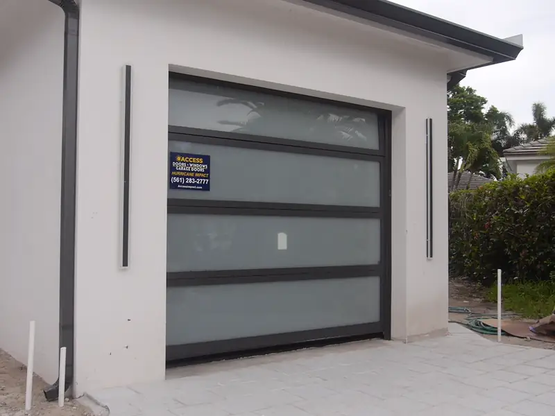 A glass garage door we installed: frosted glass in a dark aluminum frame, with our Access yard sign on the glass